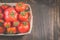 Tomatoes in a wattled basket/tomatoes in a wattled container on a dark wooden background, top view and copyspace