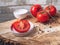 Tomatoes whole and sliced on a wooden saw stand. Coarse salt in a white vase.