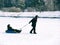 Toned image of a happy family where the mother carries a small boy on a sled in the snow