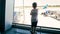 Toned image of little toddler boy looking on airplanes on runway at airport terminal
