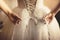 Toned photo of beautiful bride tying up her wedding dress