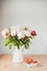 Toned photo Bunch of Pink peonies in vase and strawberry on the wooden table Flowers on a beige wooden table near the