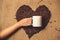 Toned photo of person holding white mug against heart of coffee