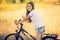 Toned portrait of beautiful girl posing on bicycle at meadow at