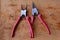 Tongs pliers with red plastic handles hang on nails on the banner canvas.