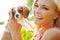 Too cute for words. Portrait of a happy beautiful blonde holding up an adorable puppy in the outdoors.