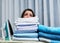 Too much to do, too little time. Shot of an anxious looking young woman behind a pile of laundry on an ironing board.