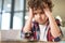 Too much to learn. Portrait of tired latin boy holding his head, looking sad while sitting at the desk and studying at