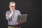 Too much work to do. Tired angry senior aged man with laptop computer isolated against black background