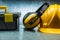 Tool box earphones and yellow construction helmet on metalic background