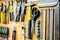 Tools and devices hanging on workshop wall. Rulers, cutting knives, scissors and other objects well arranged in working place.