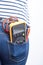 Tools for electrician in back pocket of blue jeans worn by a woman. Multimeter.