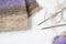 Tools for needlework: knitting fabric, tangle of thread of multicolored yarn, knitting needles. Purple, brown, white, beige colors