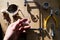 Tools set for handmade jewellery. Woman hand hold a lense. Jewelry workplace on wooden table, bright sunshine. Top view