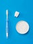 A tooth figurine, a blue toothbrush, and a jar of tooth powder on a blue background.