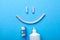 Tooth-paste in the form of a face with smile. Tube of toothpaste and toothbrush on a blue background