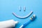 Tooth-paste in the form of a face with a smile. Tube of toothpaste and toothbrush on a blue background. Refreshing