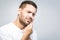 Toothache. Handsome young man suffering from toothache, closeup, touching his cheek to stop pain against white background