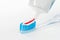Toothbrush of clear plastic with blue bristles, white blue red toothpaste squeezes out of a tube