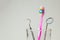 Toothbrush pink and dental tools mirror and hook in glass. Dental care and visit to dentist