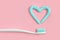 Toothbrushes and turquoise color toothpaste in shape of heart on pink background. Dental and healthcare concept.