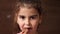 Toothless girl eats chocolate candy. A child without front teeth bites off candy. Close up