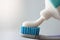 Toothpaste flowing out of white tube onto toothbrush closeup