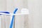 Toothpaste on toothbrush and interdental brush on clean glass on blurred wooden background in bathroom