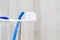 Toothpaste on toothbrush and interdental brush on wet glass on blurred wooden background in bathroom