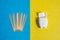 Toothpicks on blue background and dental floss in white container on yellow backdrop, top view