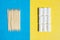 Toothpicks on blue background and group chewing gums in white container on yellow backdrop, top view