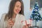 Toothy smiling woman with red lips holding gift box and vine glass.