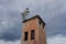 Top of an abandoned brick tower with a small birch tree on its roof. Cloudy sky on background.