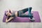 Top above high angle photo of joyful active sportive girl lie on purple mat practicing asana sport exercise make bridge