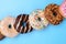 Top above overhead close up view photo of different yummy donuts lying in a row isolated over pastel color background