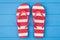 Top above overhead view close-up photo of a pair of red and white striped flipflops in center isolated on blue wooden background