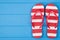 Top above overhead view close-up photo of a pair of striped flipflops placed to the right side isolated on blue wooden background