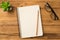 Top above overhead view photo of empty blank notepad on spiral with clear page pencil eyeglasses on table and plant laying om