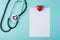 Top above overhead view photo of medical prescription paper with stethoscope beside and a heart isolated on turquoise background