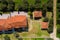 Top aerial view from above to countryside plan with red tile roofs, green trees, ground road. Yard of private residential house