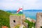 Top aerial view of Gulf of Spezia turquoise water, ancient stone wall of Castello Doria castle tower with flag in Portovenere