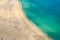 Top aerial view of sandy beach with people tourists sunbathing and Atlantic Ocean azure turquoise water, Praia da Nazare