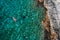 Top aerial view of the young female floating on the back and relaxing on the warm turquoise Adriatic sea waves with rocky
