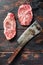 Top blade organic meat cut, raw marbled beef steak, with old butcher knife cleaver  On dark wooden rustic table, top view