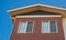 Top of a brick house with nice windows. Red brick house. Dormer in blue sky background. Real Estate Exterior Front House