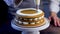 On the top cake of the cake, which has three layers, the cook from the pastry bag applies a circular white cream, a