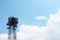 Top of a cell communications antenna tower against a blue sky with clouds
