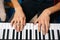 Top close-up view of hands of unrecognizable musician man playing on piano at home. Concept of music education.