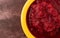 Top close view of a bowl of beets and pears baby food on a maroon background