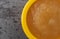 Top close view of a small yellow bowl filled with applesauce on a gray background